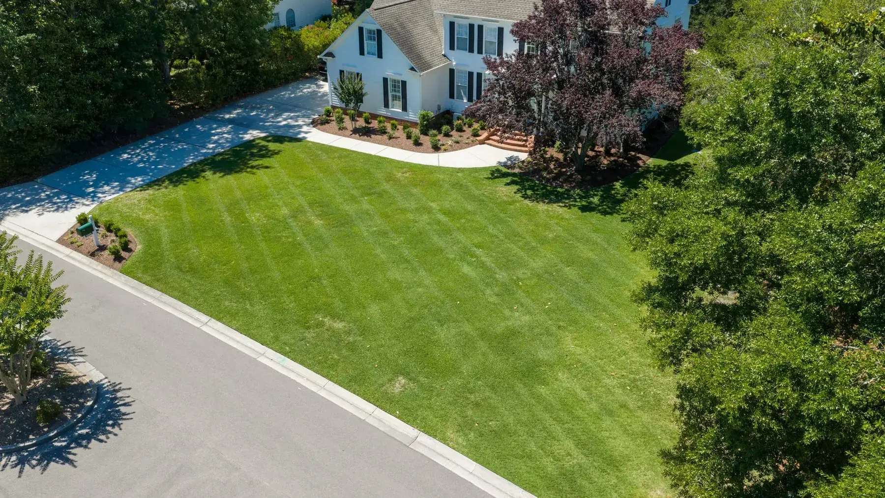 Striped lawn running the full front of a white two-story home